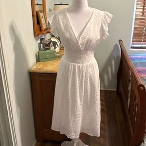 NWOT totally lined, white eyelet dress with rufflled sleeves. V neck. Size M.